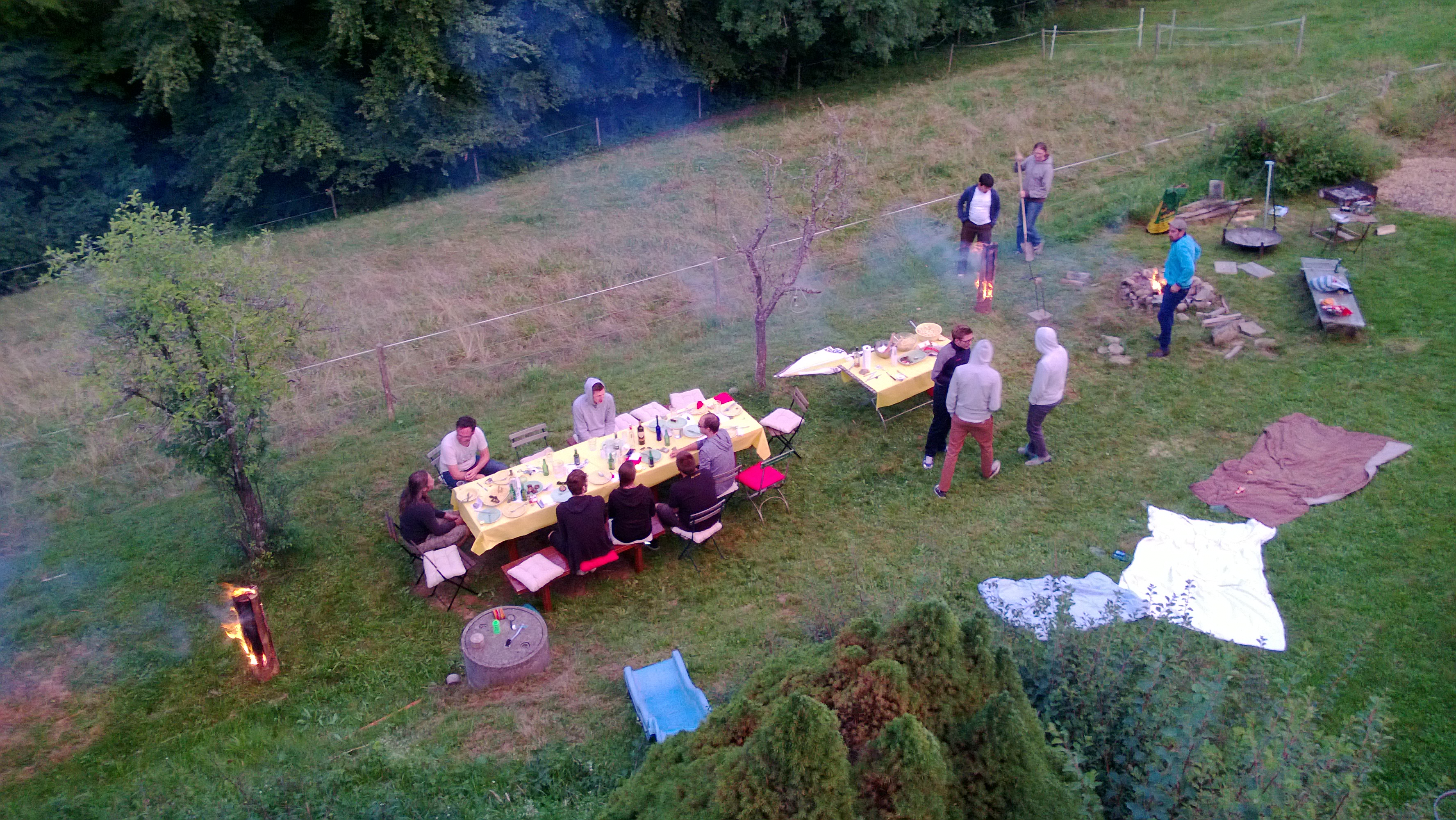 Vogelperspektive von Leuten an einem langen Tisch im Garten