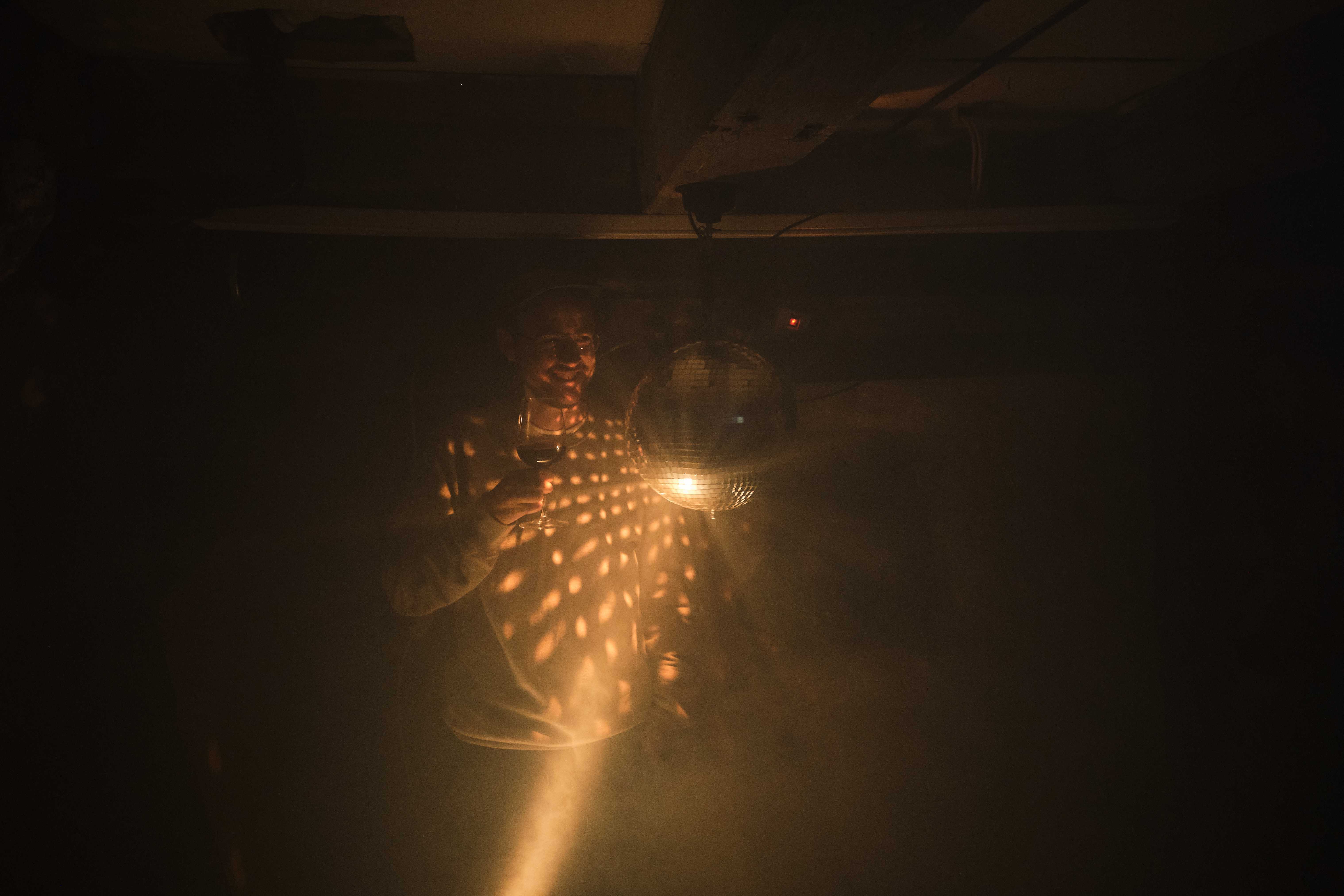 Stefan Spieler mit einem Glas Wein neben einer Discokugel