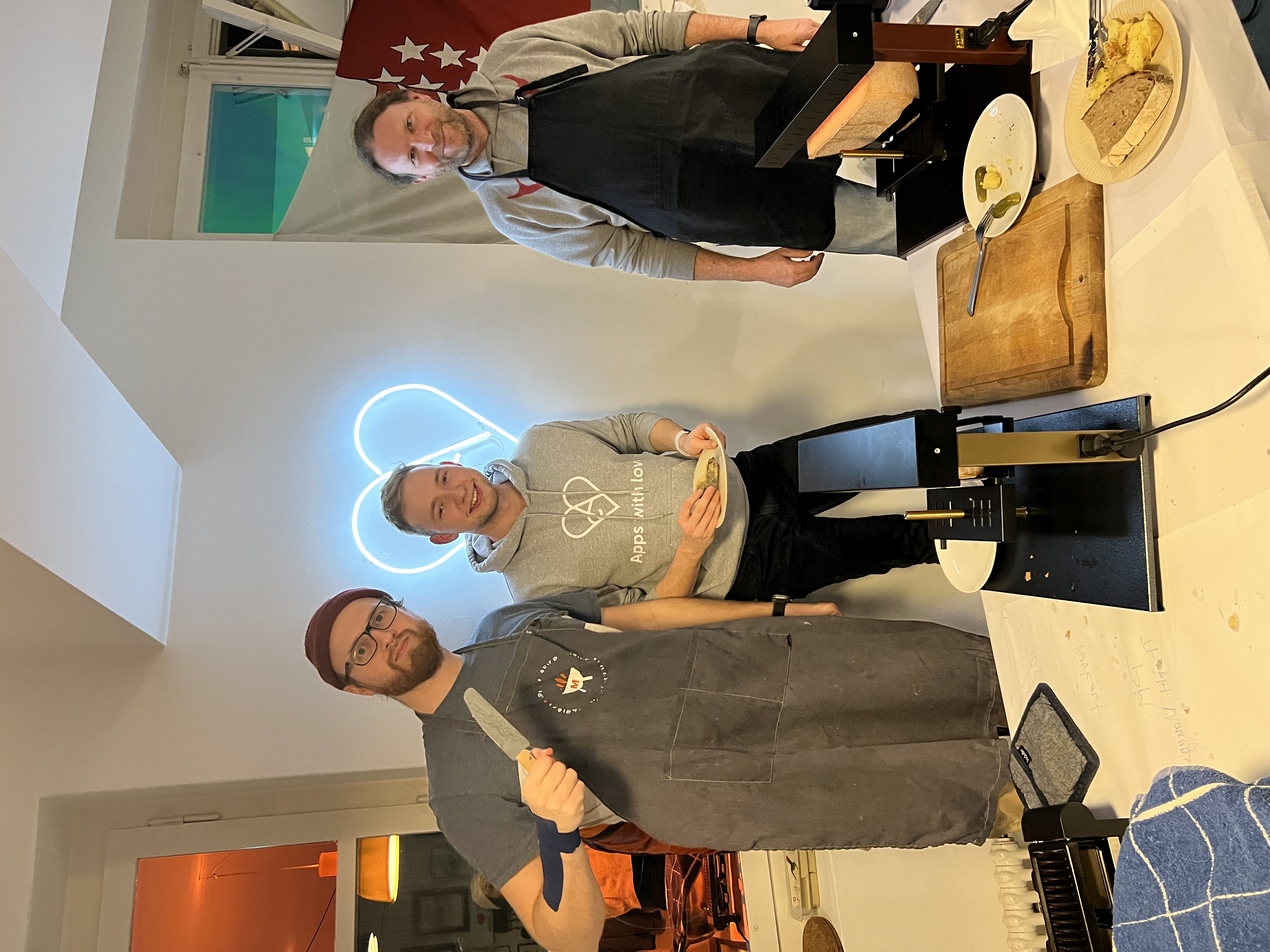 Simon, Alain und Oli stehen hinter einem Tisch mit 2 Racletteofen