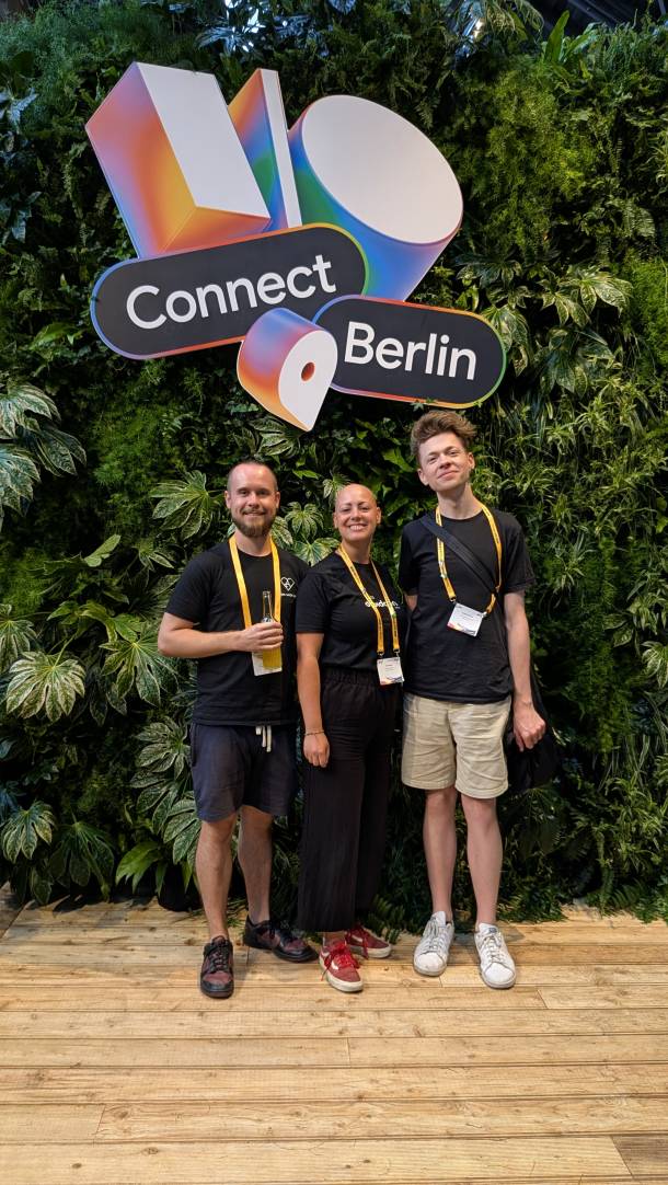 Ossi, Dinah und Yannick stehen vor einer begrünten Wand, über ihnen das Google I/O Connect Logo