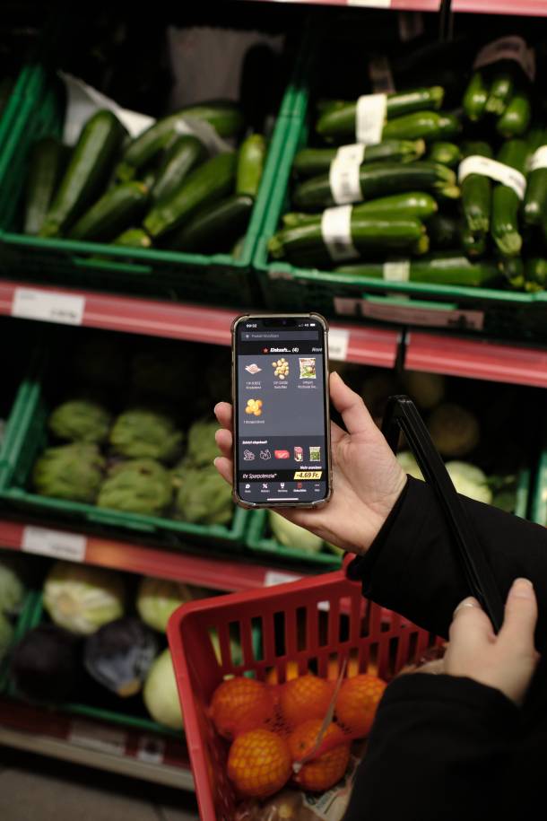 Personne qui achète des légumes selon une liste d'achats Denner