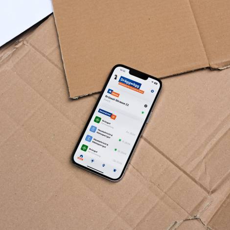 Dräggwägg App geöffnet auf einem iPhone, das auf Karton liegt.