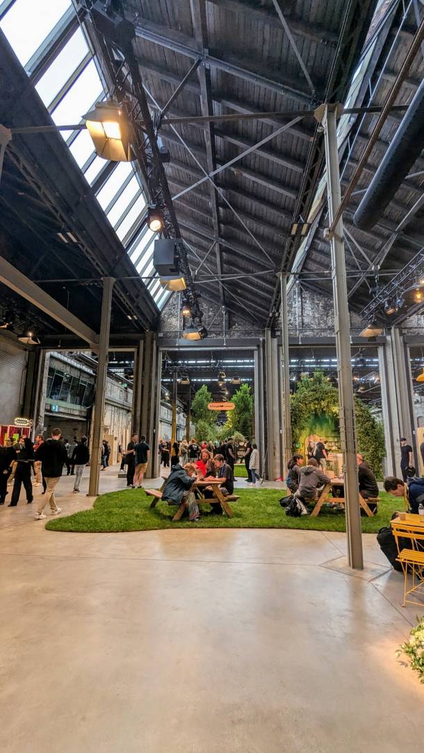 Einblick in die Halle der Google I/O Connect, Leute sitzen an Picnic Tischen