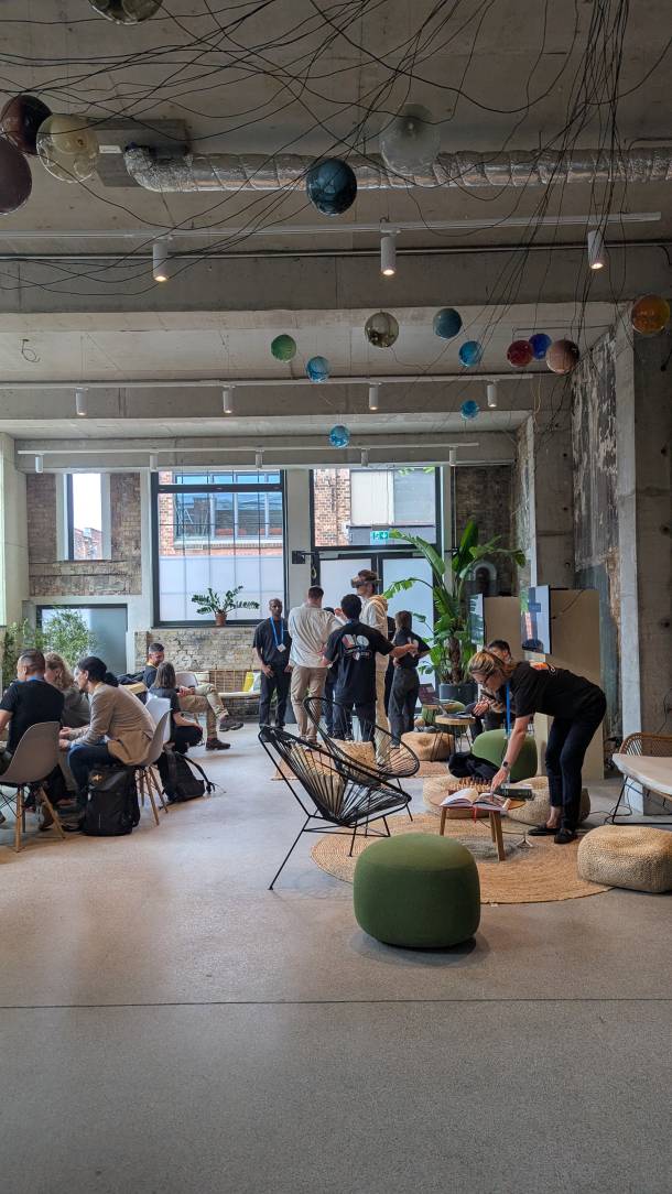 Lounge Bereich in welchem Leute miteinander reden, jemand probiert das Samsung VR Headset Project Moohan an