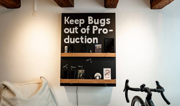 Bild eines Gestells mit Smartphones und Tablets. Das Gestell ist angeschrieben mit "Kepp Bugs out of Production"